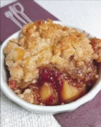 Slice of apple cranberry dump cake with gooey fruit filling and walnut topping