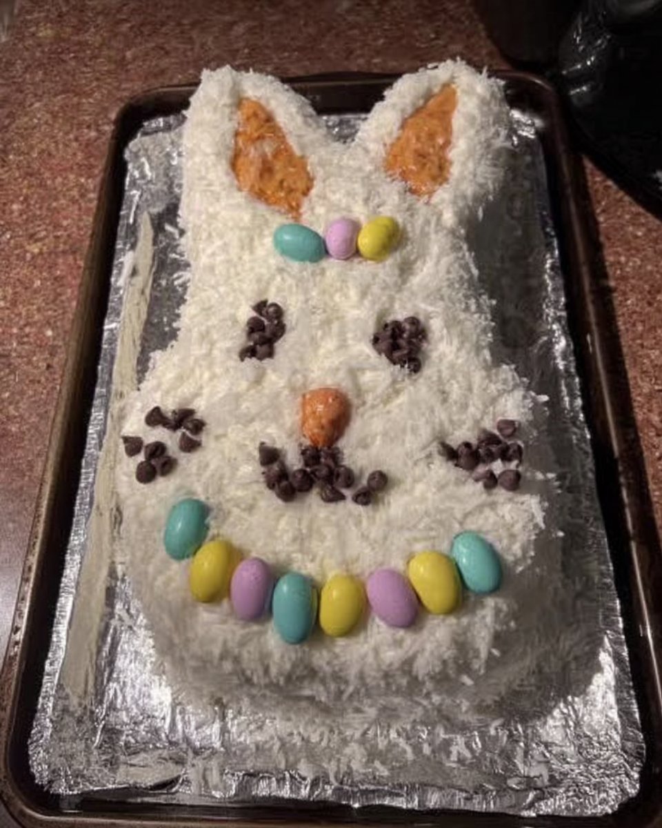 Using a toothbrush to flick cocoa speckles onto a blue frosted cake