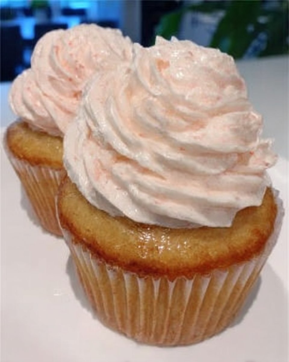 Whole frosted pink champagne cake with decorative swirls and sprinkles