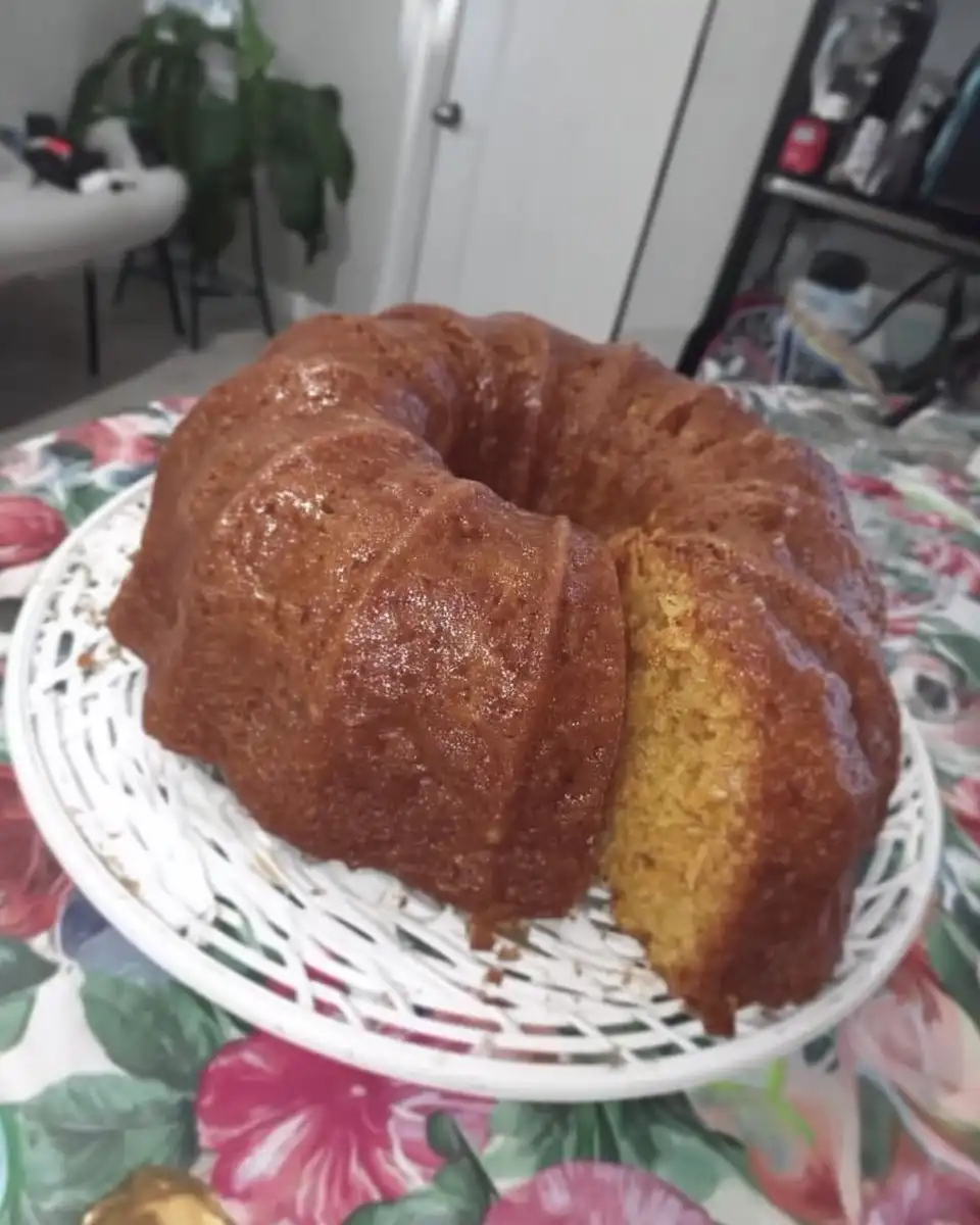 Whole frosted vanilla cake on a ceramic stand