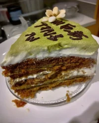 Slice of green tea cake with cream cheese frosting on a white plate