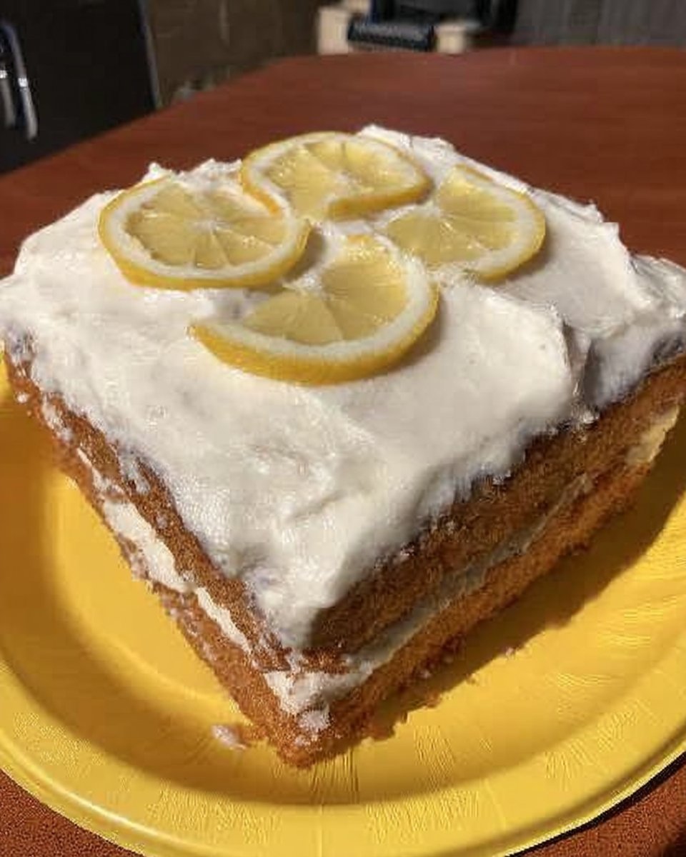 A slice of Lemon Cake 2 on a ceramic plate showing moist yellow crumb
