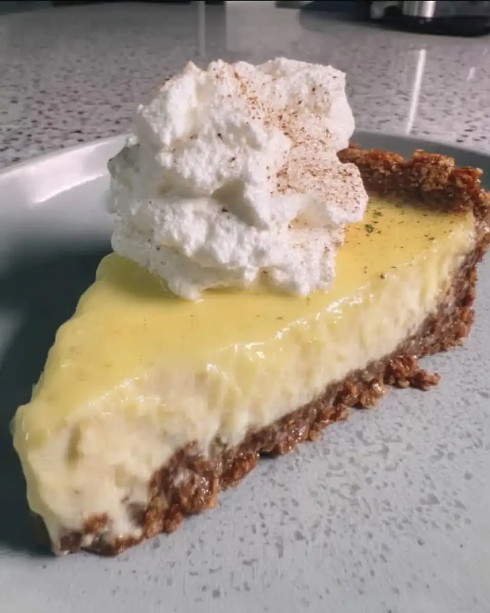 Pouring bright yellow lemon curd over the cheesecake