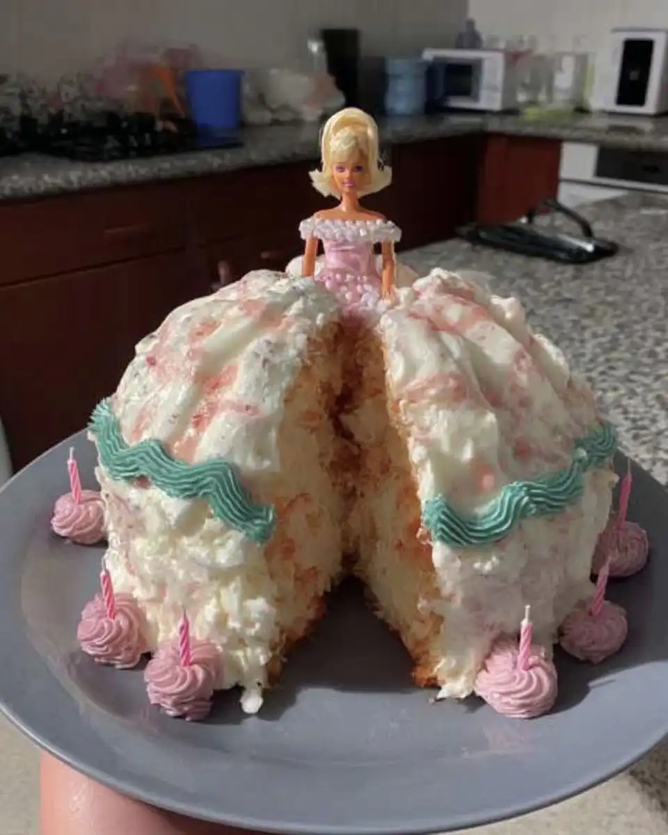 Barbie Cake 14 A slice of moist yellow cake with pink frosting on a plate