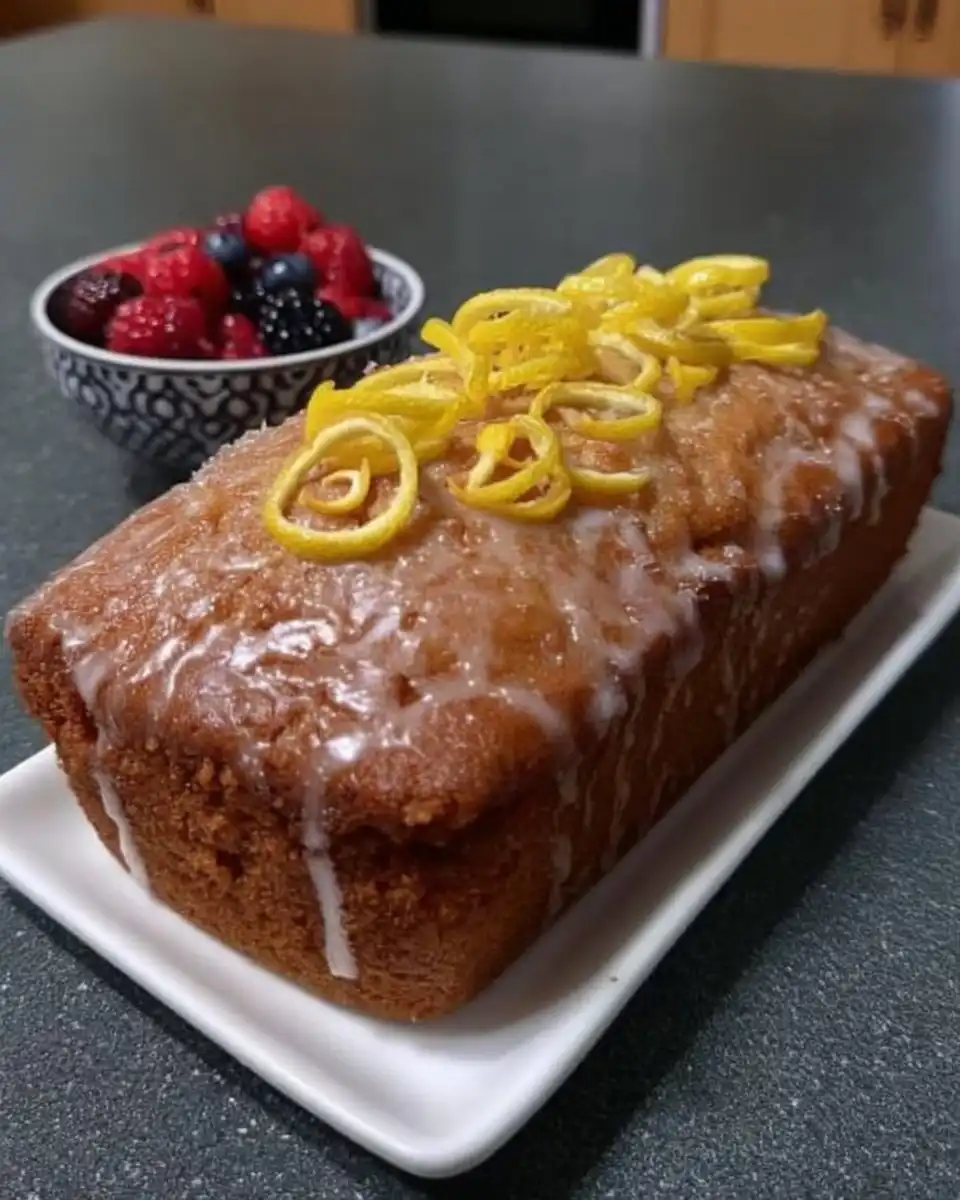 Two slices of lemon drizzle cake on a ceramic plate with a fork