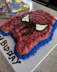 Spider Man face cake covered in red fondant with white eyes
