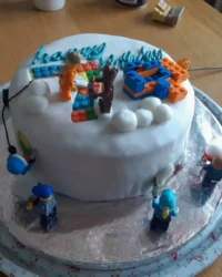 A rectangular cake decorated like a green soccer pitch with player figurines and a ball