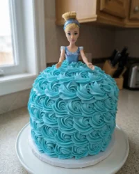 A beautiful Cinderella cake with sky blue rosette frosting and a doll centerpiece