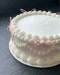 A vintage style coquette cake with pink buttercream ruffles and silk bows