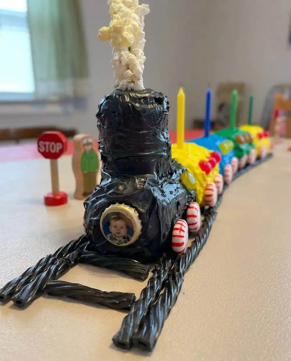 Hand decorating a train cake with blue and red buttercream