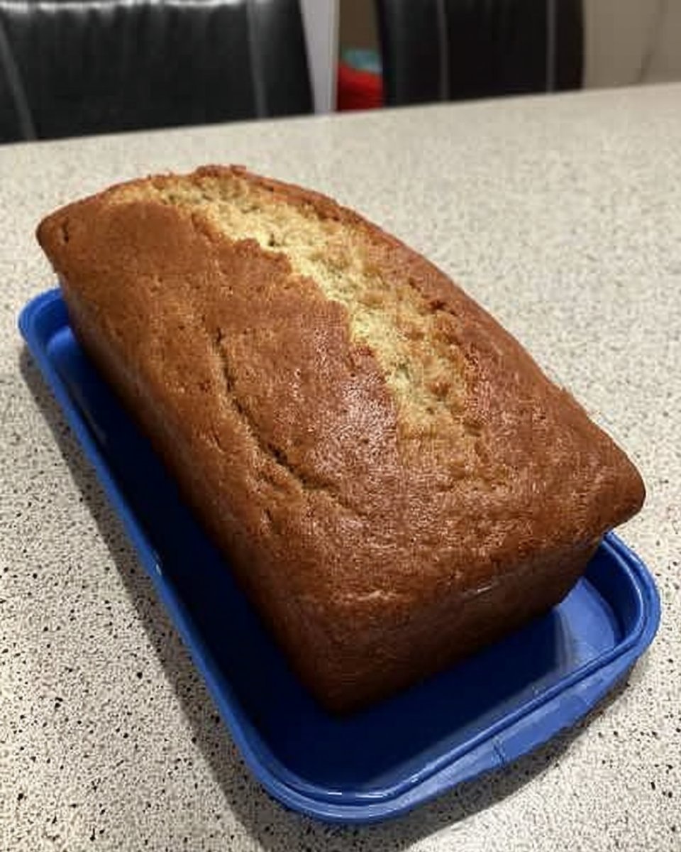 Thick white lemon glaze being poured over a round yellow cake