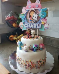 A colorful and vibrant Gabbys Dollhouse Cake with pink frosting and sprinkles