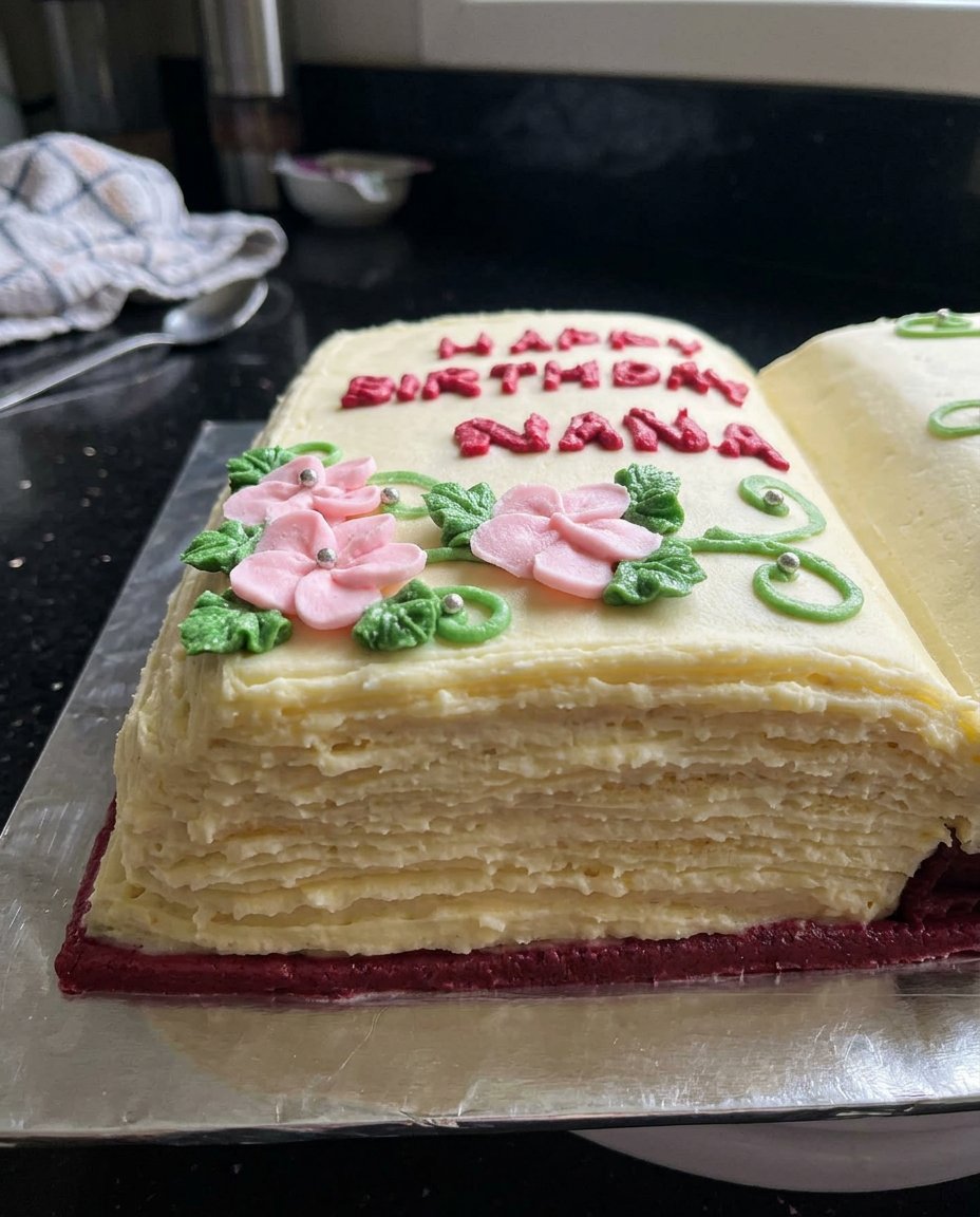 Ingredients for a book cake including butter, cocoa powder, eggs, and flour on a marble surface