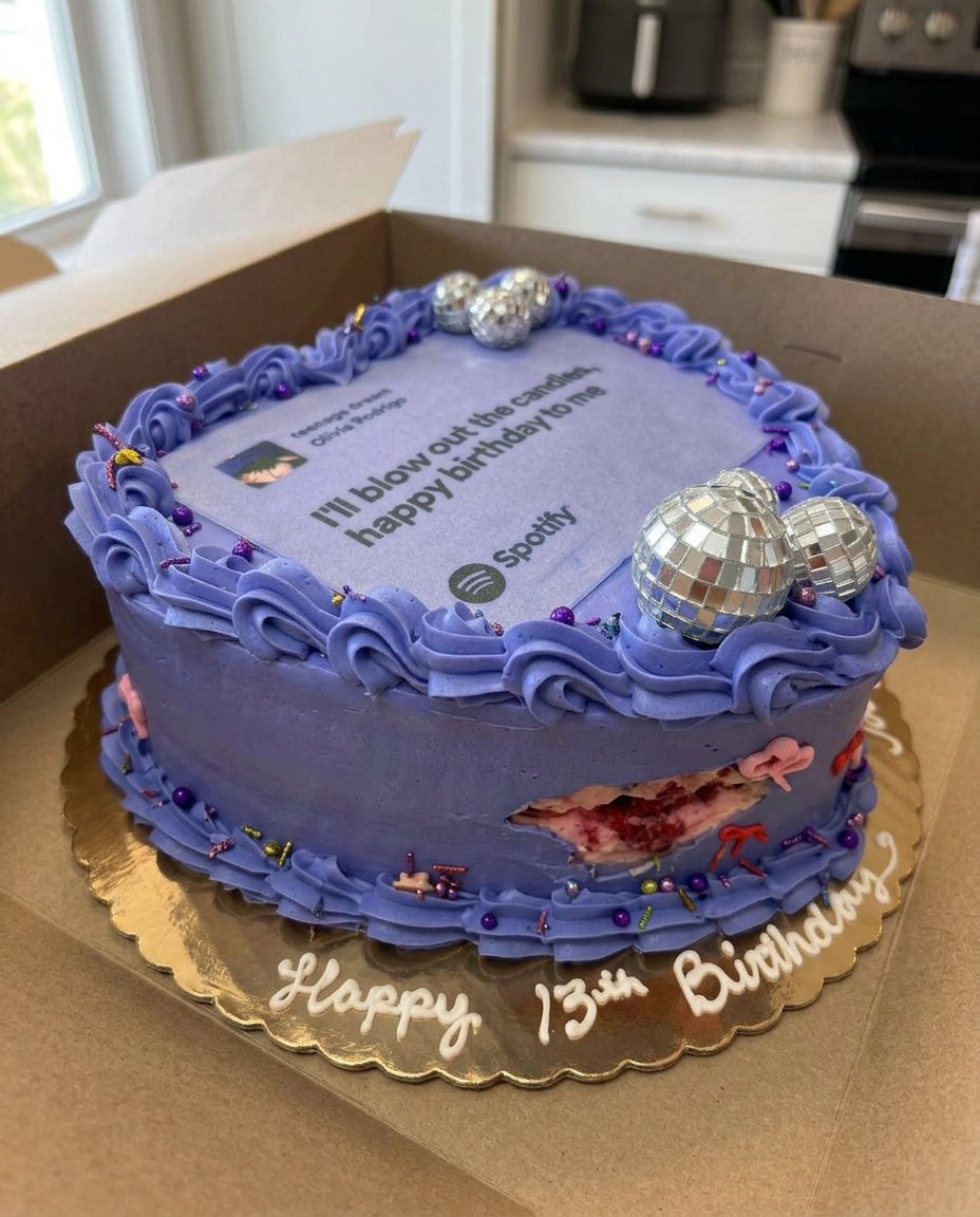 A four layer purple Olivia Rodrigo cake with a Spotify topper and ribbon bows