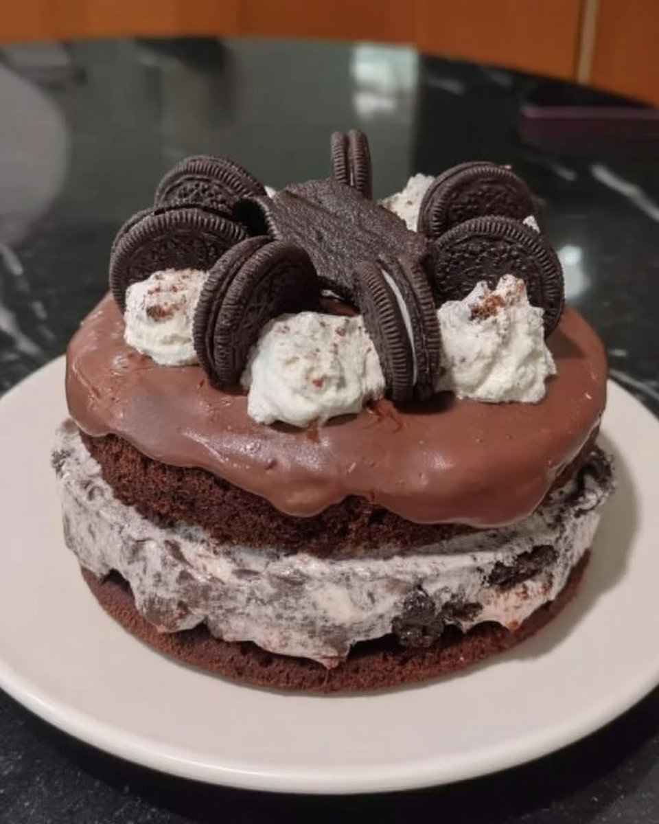 A cross section of a three layer Oreo Cake with white sponge and dark cookie pieces