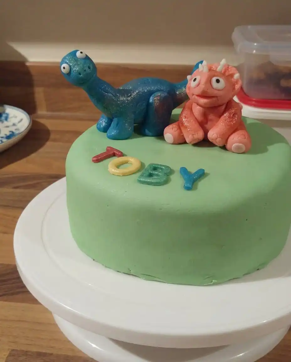 Boys Cake 13 Close up of a piping bag with a grass nozzle creating green frosting tufts on a cake