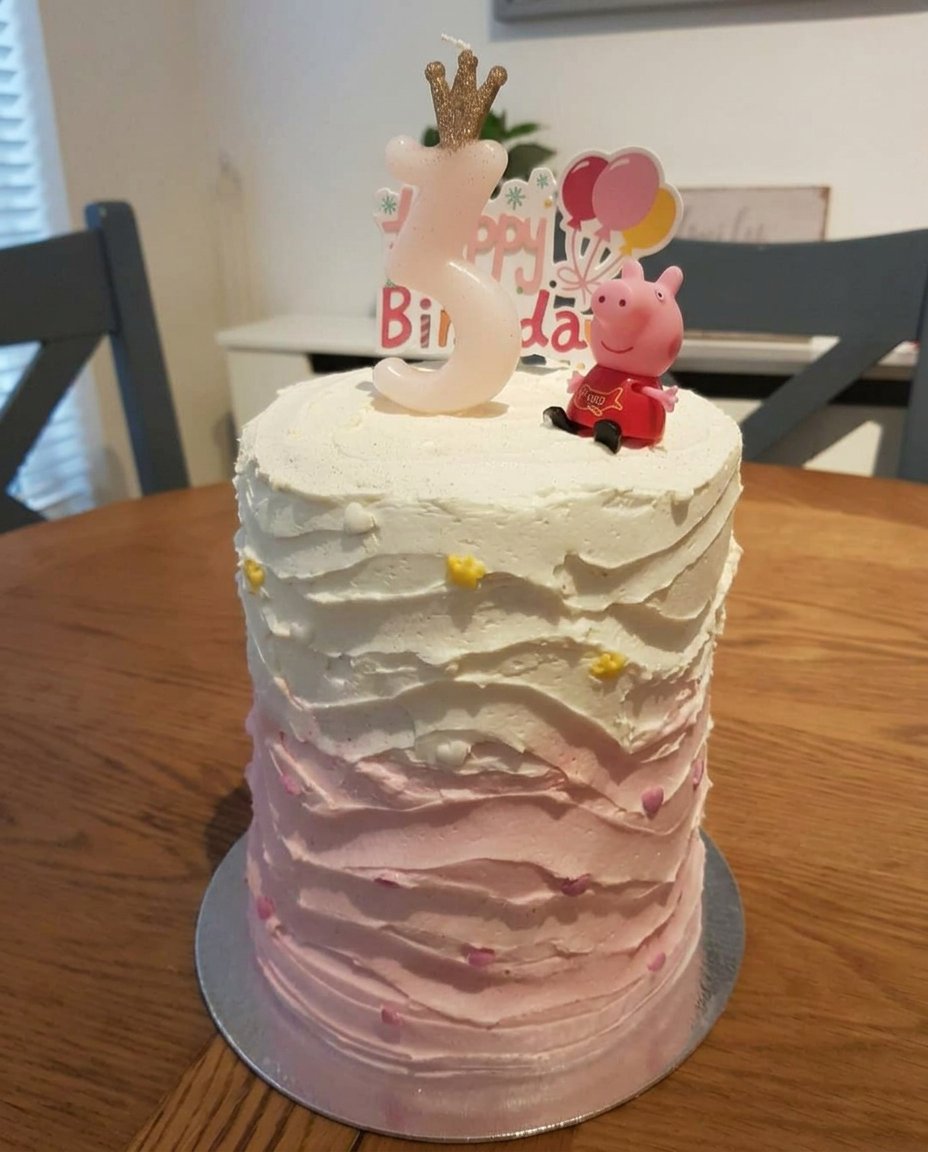 Girl Cake 13 A close up of a piping bag creating pink rosettes on a cake