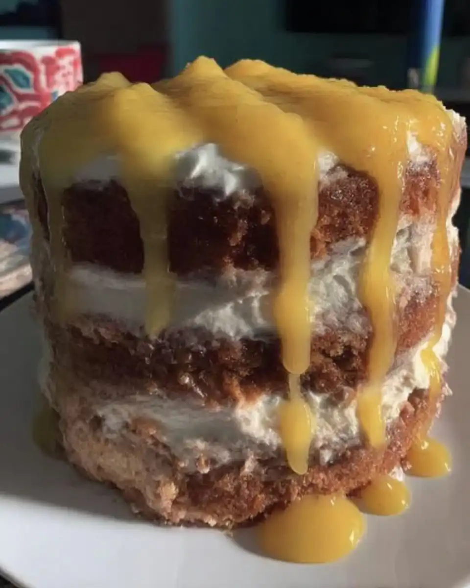 A single slice of lemon rainbow cake showing the colorful layers and orange frosting