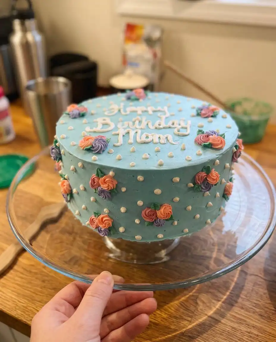 A tapered spatula applying white icing petals to a cake side