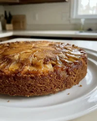 A golden apple spice cake in a glass pan with visible cinnamon apple slices