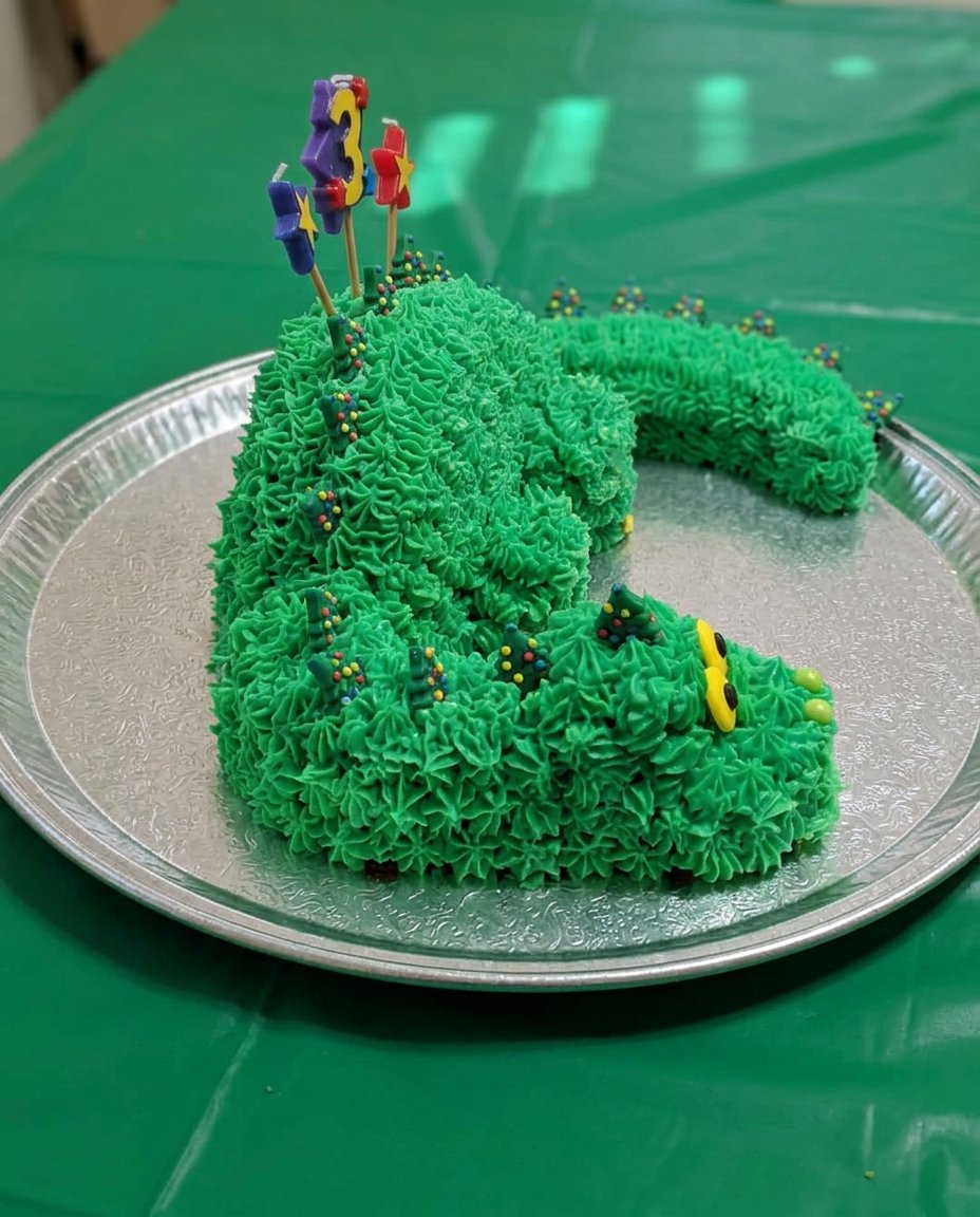A slice of turquoise dino cake being served on a plate