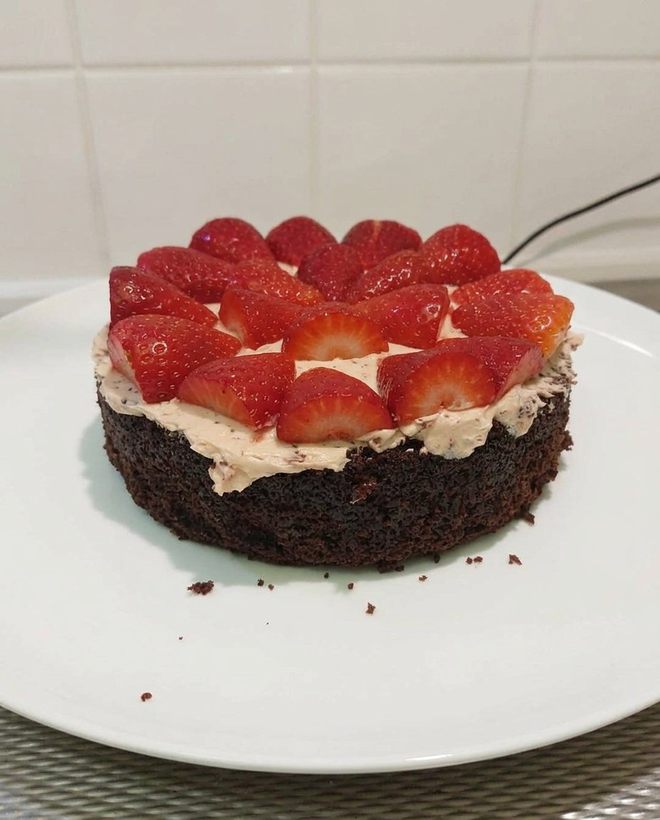 Pink strawberry buttercream in a glass bowl being whipped with a whisk