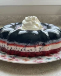 A vibrant red strawberry jello cake in a bundt shape with fresh strawberry slices