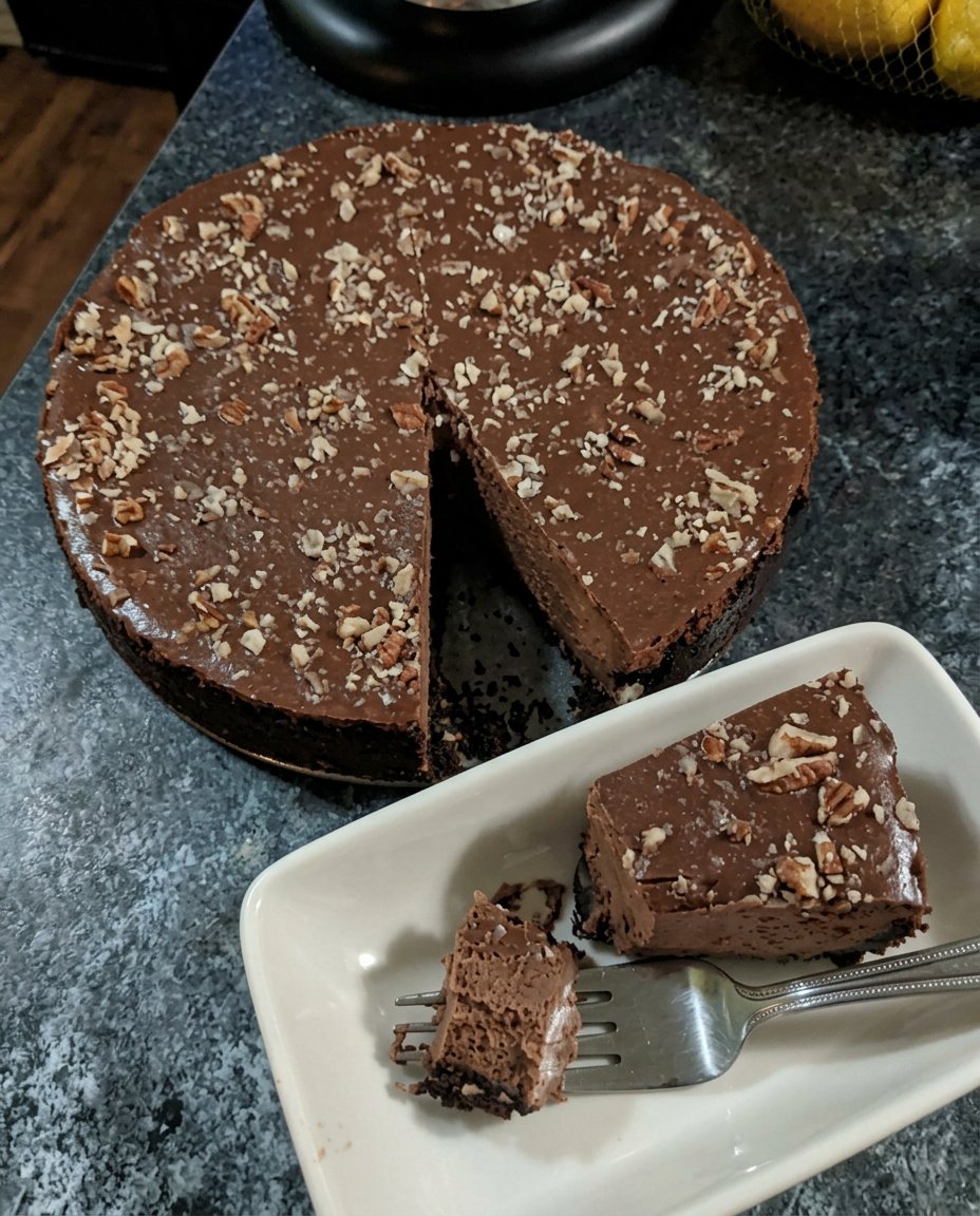 A slice of chocolate truffle cake showing a moist sponge base and thick whipped ganache layer