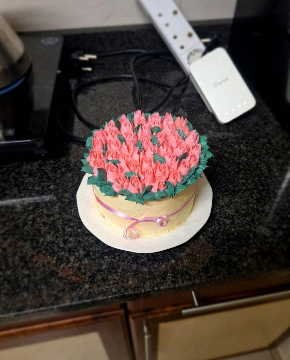A slice of tulip cake on a decorative plate next to a cup of coffee.
