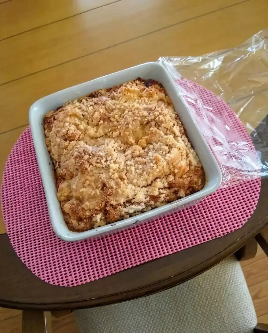A single slice of strawberry rhubarb cake served on a white plate with a dollop of whipped cream.