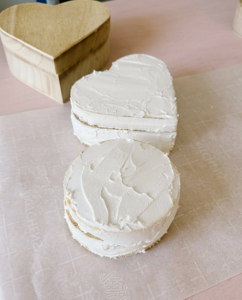 Fake Cake 13 Smoothing pink strawberry frosting on a layered cake with a scraper