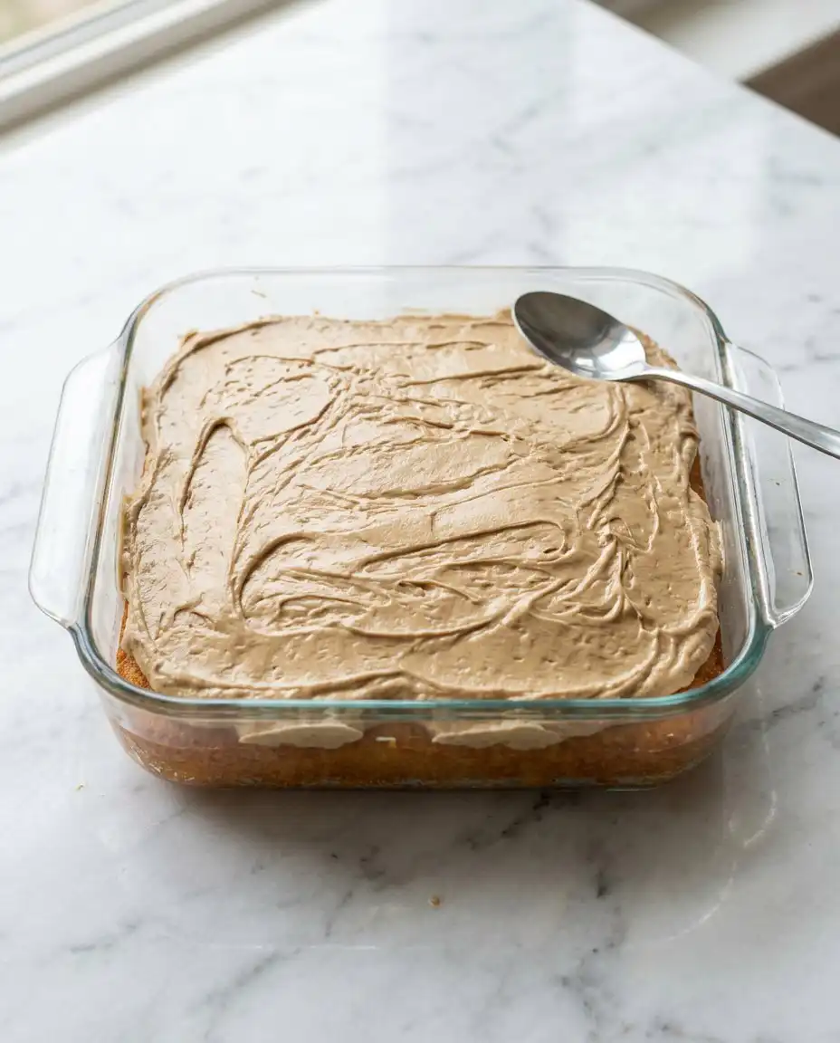 A slice of Peach Cake with Brown Sugar Frosting next to a cup of dark coffee.