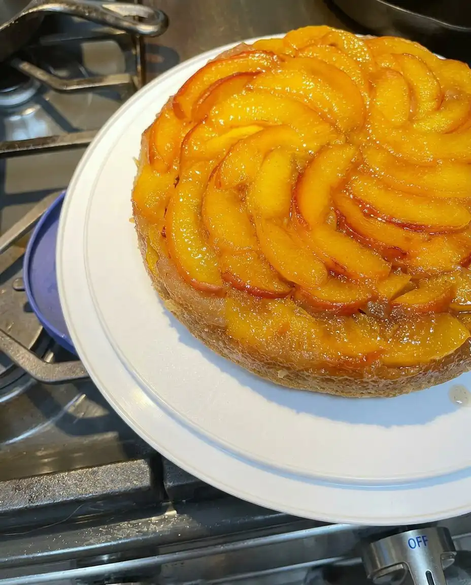 A slice of peach cake served on a plate with a cup of coffee.
