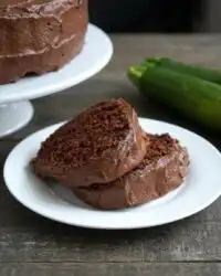 A whole Chocolate Lover's Zucchini Cake with chocolate frosting on a serving platter