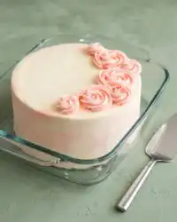 A beautiful three tiered Rose Water Layer Cake with pink watercolor frosting and rosettes.