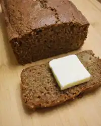 A thick slice of moist apple zucchini bread sitting on a wire cooling rack.