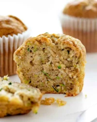 A batch of golden brown banana zucchini muffins cooling on a wire rack
