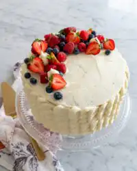 A close up shot of a slice of Chantilly Cake with fresh strawberries and whipped cream.