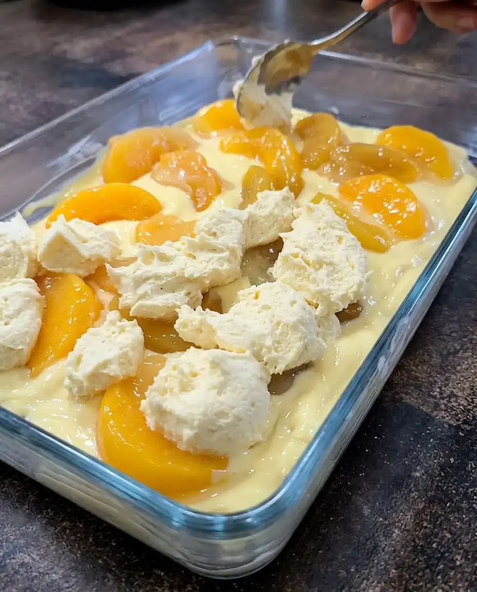 A hand drizzling white glaze over golden Peaches and Cream Bars.