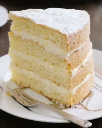 A slice of Italian Lemon Mascarpone Layer Cake showing airy sponge and creamy layers.
