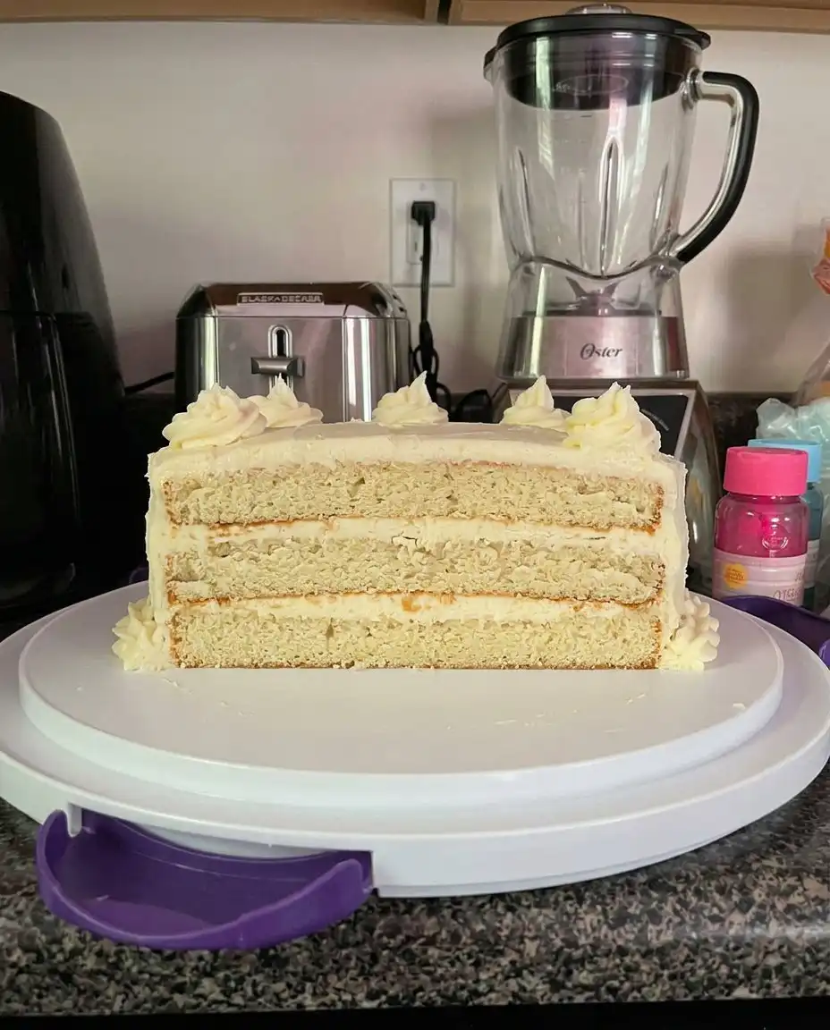 A slice of lemon velvet cake next to a cup of dark Turkish coffee on a sunny terrace.