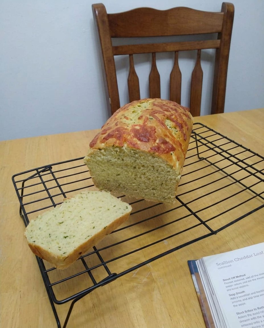 A close up of a slice of zucchini cheddar bread showing the moist crumb