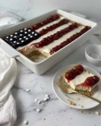 Slice of no-bake American flag cheesecake with gooey cherry and blueberry topping