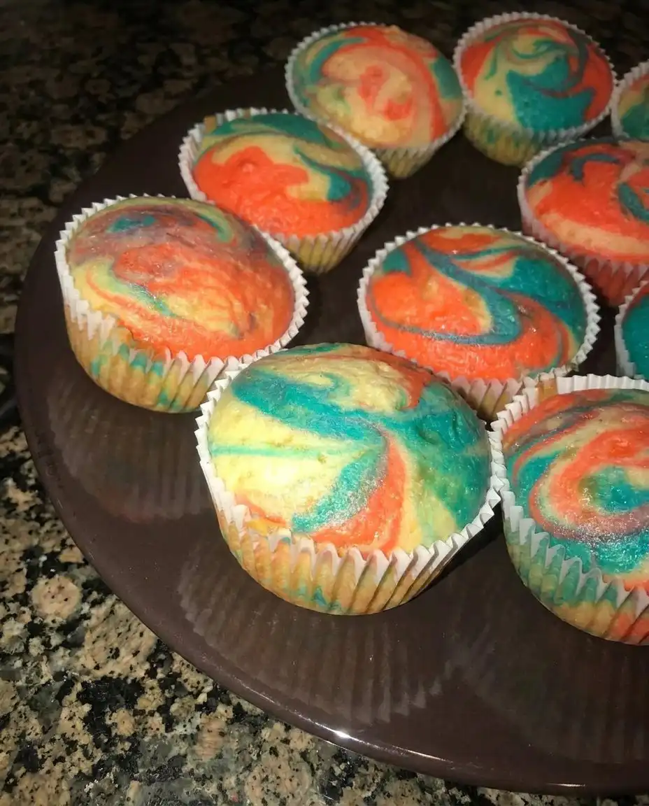 Piping blue and white frosting onto chocolate cupcakes