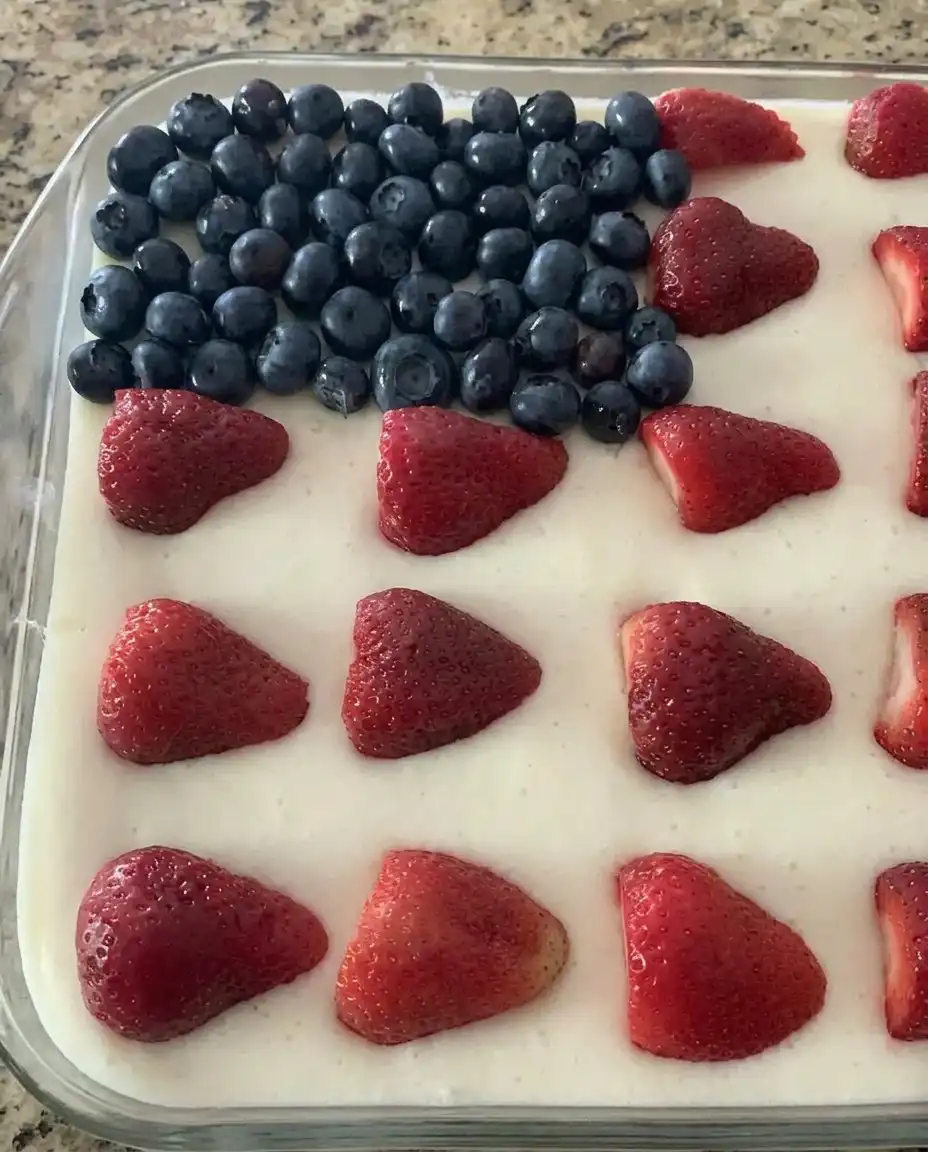 Strawberry Jello American Flag Cake 14 A square slice of flag cake on a white plate with a fork gliding through.