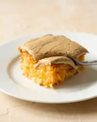 A square of Peach Cake with Brown Sugar Frosting served on a white ceramic plate.