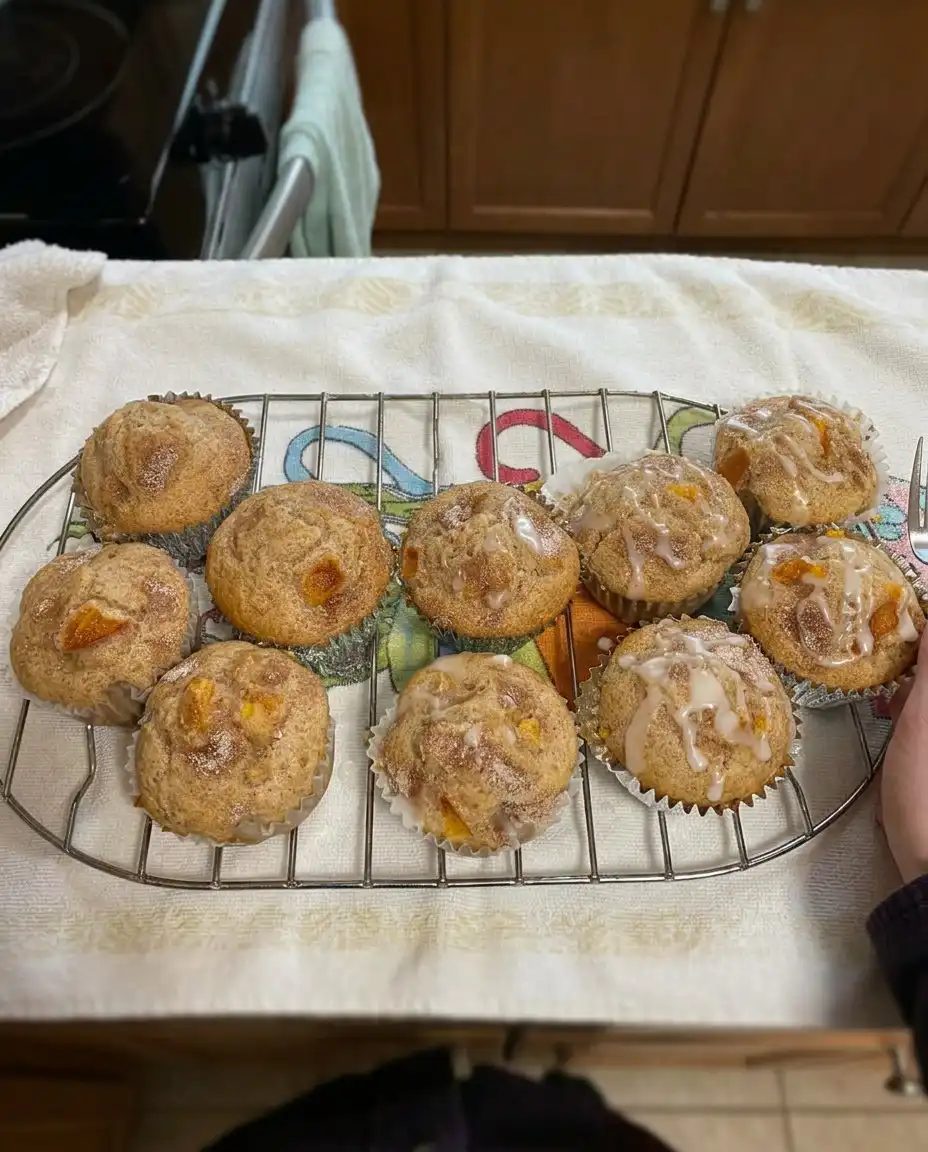 A single peach cobbler muffin served on a ceramic plate with a cup of coffee