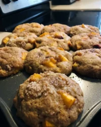 Close up of a golden peach cobbler muffin with a crunchy streusel topping