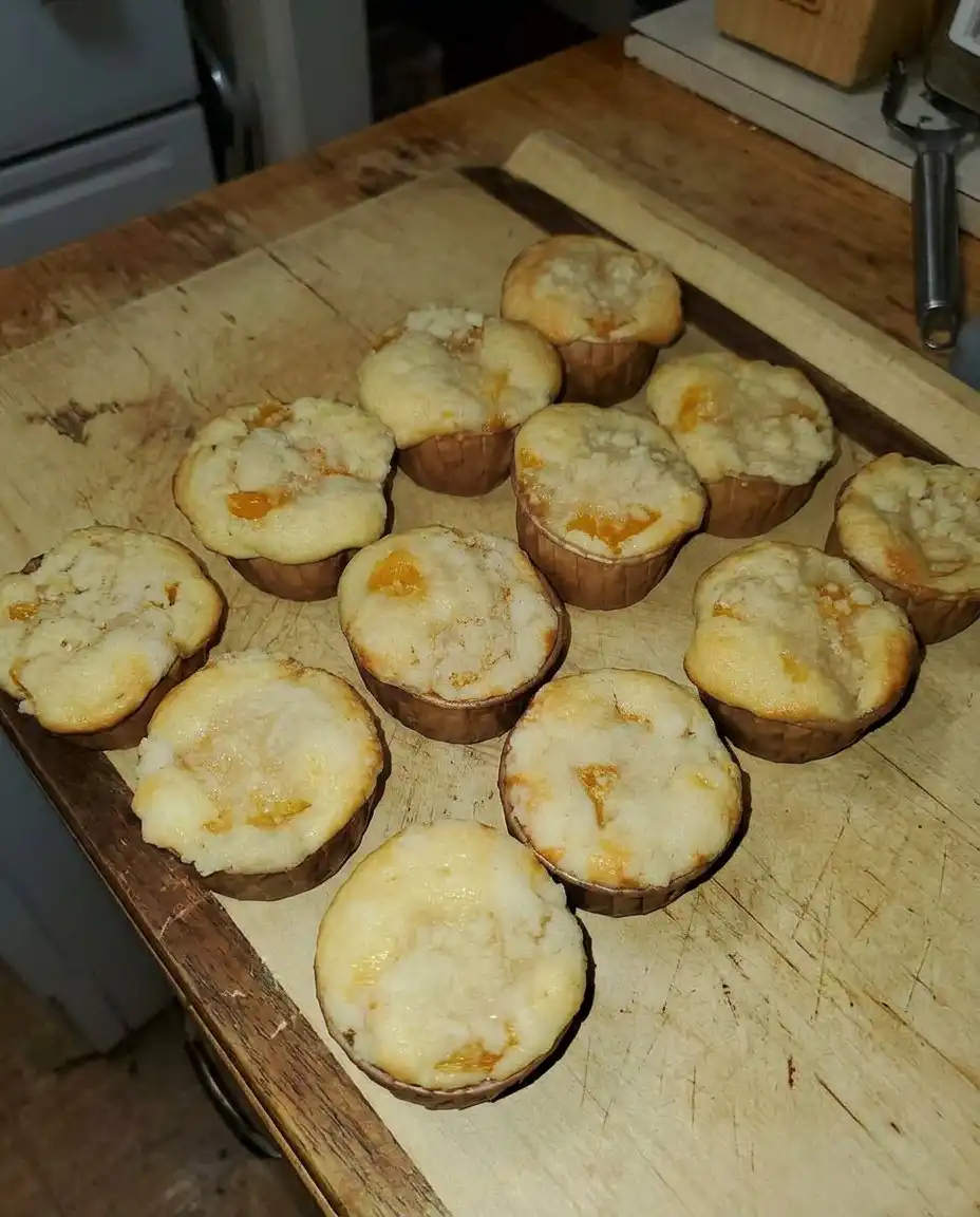 Canned peach cobbler muffins served on a platter next to a cup of coffee.