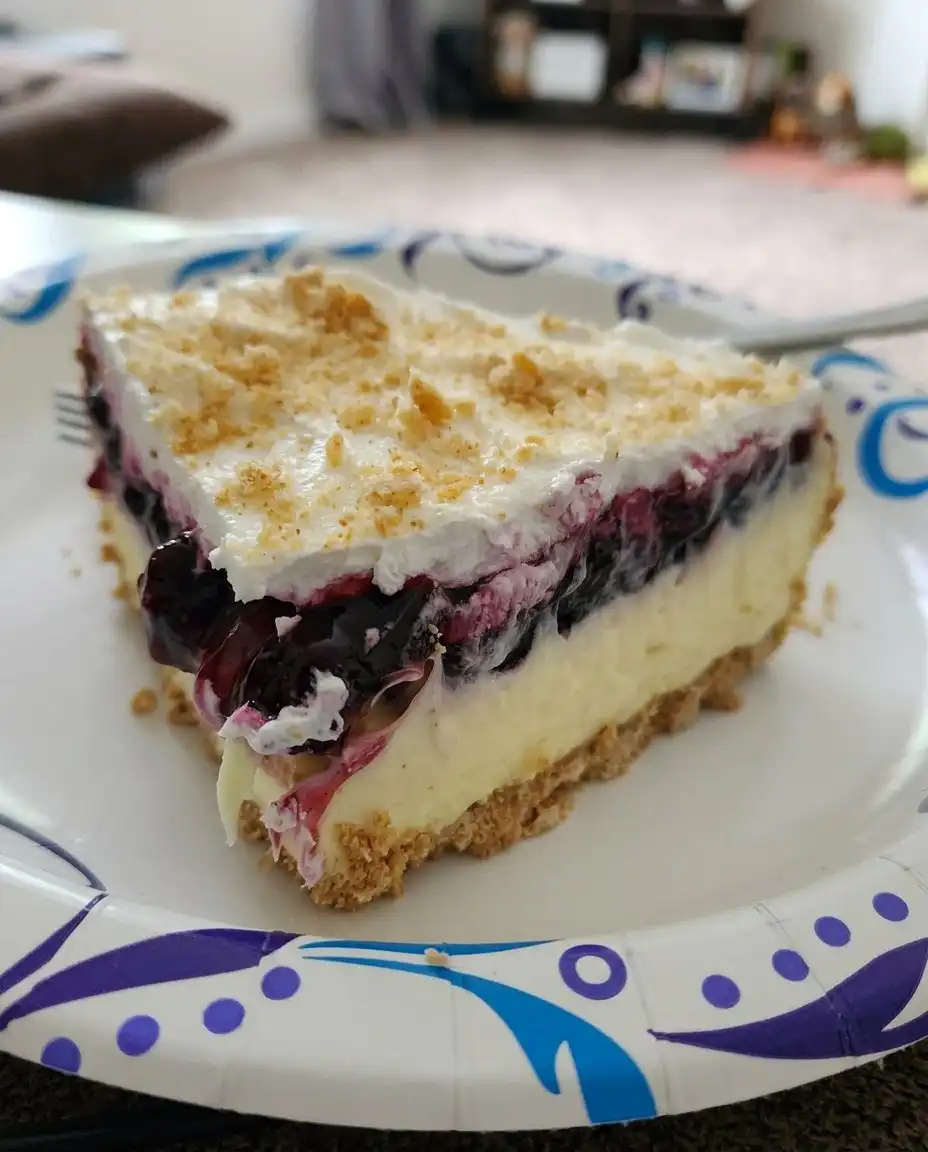 No Bake Lemon Blueberry Dessert 14 A clean square slice of lemon blueberry dessert on a white plate with fresh blueberry garnish.